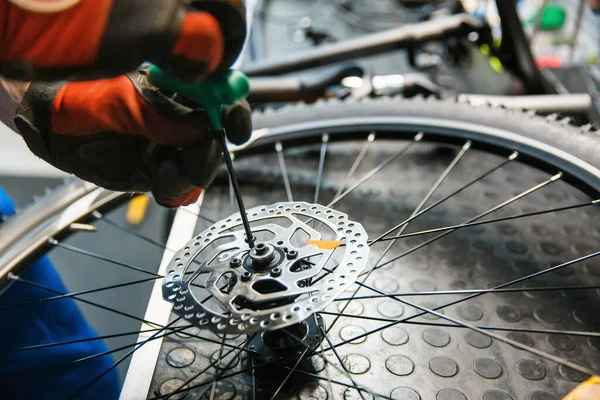 ワークショップで自転車の組み立て 男はブレーキディスクをインストールします サイクル プロの自転車修理サービスで均一な修正問題の機械 — ストック写真