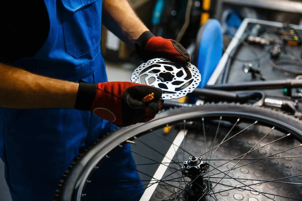 ワークショップでの自転車修理ブレーキディスクを固定する男 サイクル プロの自転車修理サービスで均一な修正問題の機械 — ストック写真