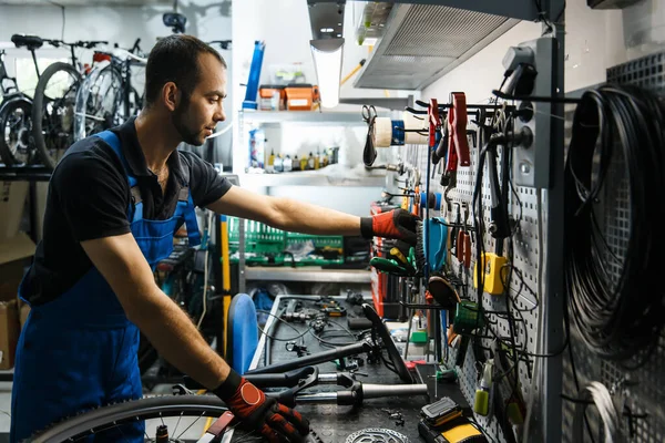 Fahrradreparatur Der Werkstatt Mann Holt Werkzeug Aus Regal Mechaniker Uniform — Stockfoto