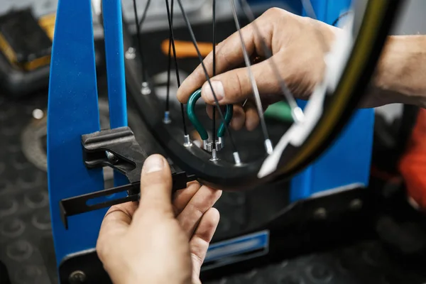 ワークショップでの自転車修理 男は車輪の上にスポークを締めます サイクル プロの自転車修理サービスで均一な修正問題の機械 — ストック写真