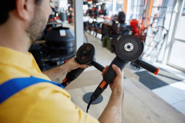 Parlak sarı gömlekli bir adam iki elinde de öğütücü tutuyor ve kullanmaya hazırlanıyor.