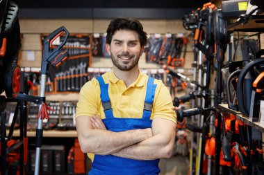 Bir mağazada kolları çapraz duran genç bir erkek işçi atmosfere giriyor.