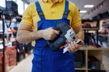 İş kıyafetleri içinde elinde yapboz tutan bir adam. Tahta ya da malzeme kesimi içeren bir projeye başlamaya hazır.