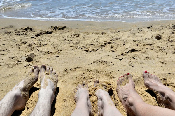 Ноги Трьох Людей Лежать Піску Перед Морем — стокове фото