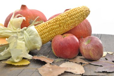 Mısır, elma ve beyaz arka plan üzerinde ahşap bir masa koymak kabaklar