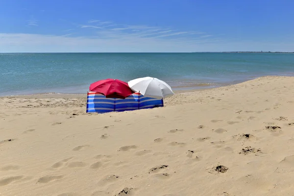 Δύο ηλιόλουστες αποχρώσεις που απομονώνονται μπροστά από τη γαλάζια θάλασσα σε μια αμμώδη παραλία — Φωτογραφία Αρχείου