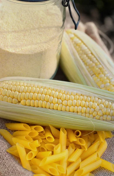 Mazorca fresca de maíz, harina en un frasco y pasta sin gluten en la tela — Foto de Stock