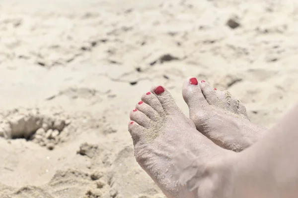 Жіноча нога з червоним лаком для нігтів на піску — стокове фото