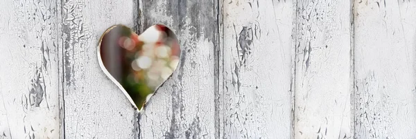 Heart-shaped hole on a door white paint defreshed in panoramic size — Stock Photo, Image