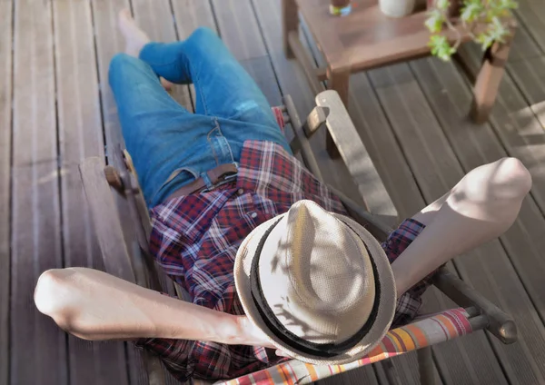 Top utsikt på en man bär hatt koppla av på en solstol på en träterrass — Stockfoto