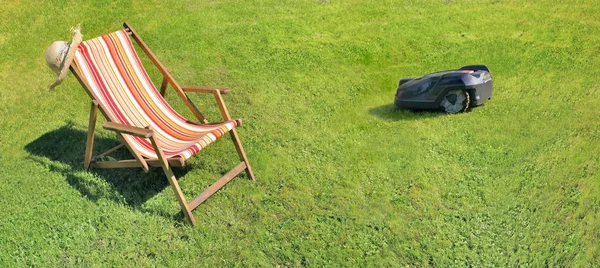 緑の草のデッキチェアと芝生の上のロボット芝刈り機 — ストック写真