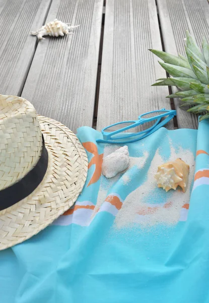 Chapeau de paille sur serviette de plage avec lunettes de soleil et ananas sur terrasse en bois — Photo