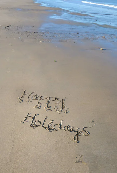 Щасливі свята написані на піску при низькому припливі — стокове фото