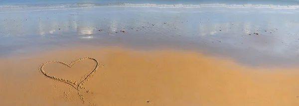 Heart drawing on the sand in front of the sea — Stock Photo, Image