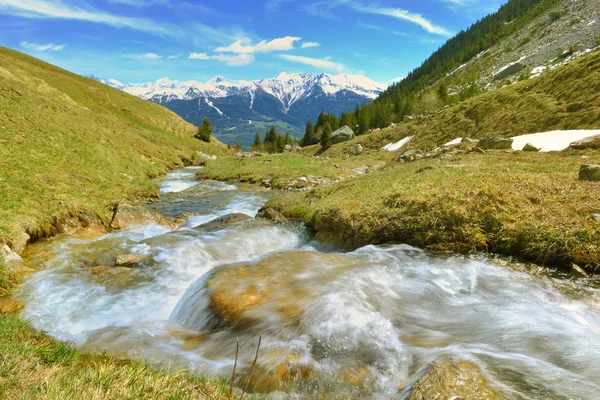 Water van een alpine stroom stroomt in Berg en besneeuwde pieken achtergrond — Stockfoto