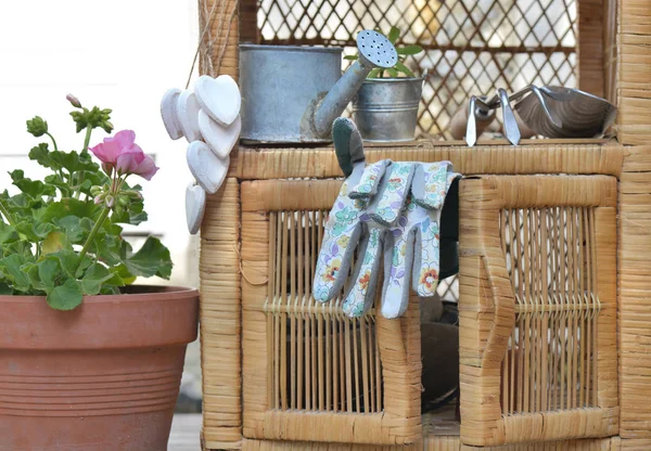 Guantes de jardinería y otros accesorios en un pequeño mobiliario de mimbre al aire libre en la terraza — Foto de Stock