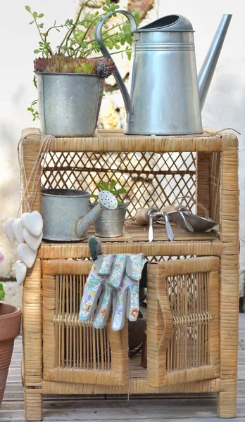 Gants de jardinage et autres accessoires sur un petit mobilier extérieur en osier en terrasse — Photo
