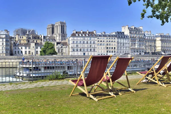 Yangın ve tur tekne sonra Paris binaları ve Notre Dame katedralönünde çim üzerinde şezlong — Stok fotoğraf