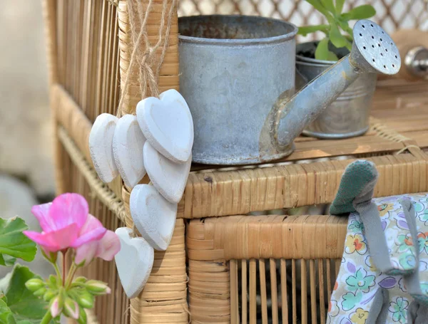 Decorativo corazón blanco en forma de colgar a un jardín muebles de mimbre con otros accesorios y plantas — Foto de Stock