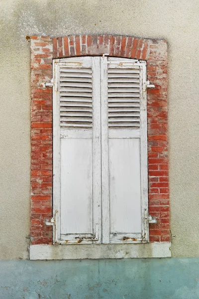 white old shutters closed on a window on house facade