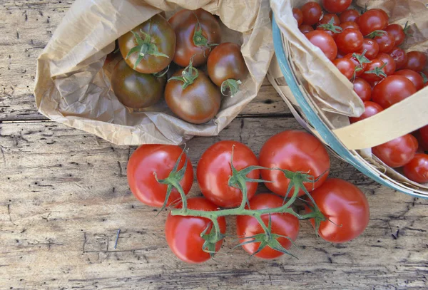 Vista superior em tomates frescos em uma cesta pequena em um fundo rústico de madeira — Fotografia de Stock