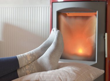 bir odun sobası ısı önünde rahatlatıcı çorap bir kadının ayakları üzerinde görünümü 