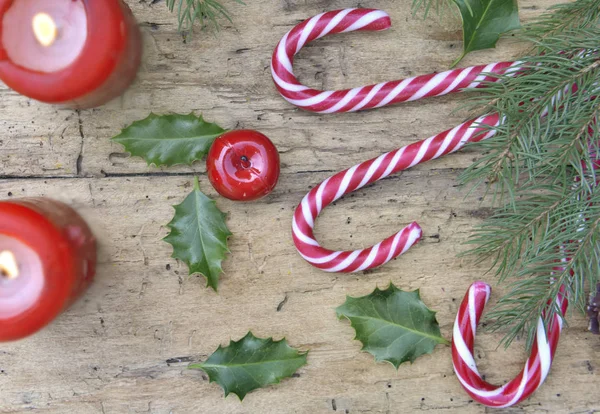 Top view on candy canes and christmas decoration with canddles on rustic plank — Stock Photo, Image