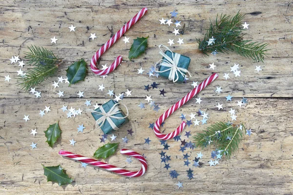 Vue de dessus sur les cannes à bonbons et la décoration de Noël en forme d'étoile confettis sur rustique — Photo