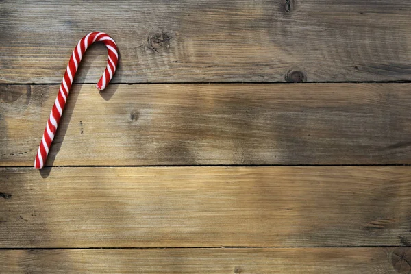 Single red candy cane on a brown rustic plank — Stock Photo, Image