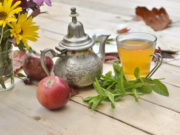 Secangkir teh dengan daun mint segar di atas meja kayu di dekorasi musim gugur — Stok Foto