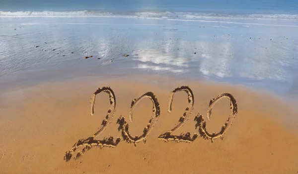 2020 handschrift op het zand naar het strand met oceaan achtergrond — Stockfoto