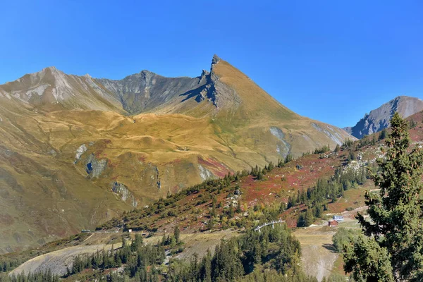 Vista na montanha alpina coberta de amarelo e vermelho no outono sob o céu azul — Fotografia de Stock