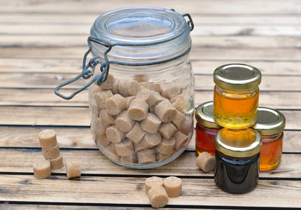 Pequenos potes de vidro de vários mel e açúcar mascavo em um t de madeira — Fotografia de Stock