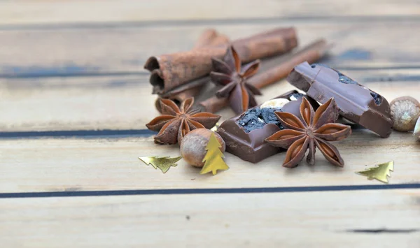 Groep kruiden en chocolade met kerstconfetti op een houten tafel — Stockfoto