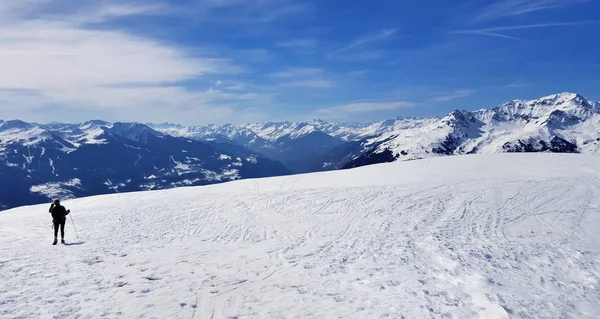 Kleine Silhouette eines Wanderers im schneebedeckten Berg unter blauem Himmel — Stockfoto