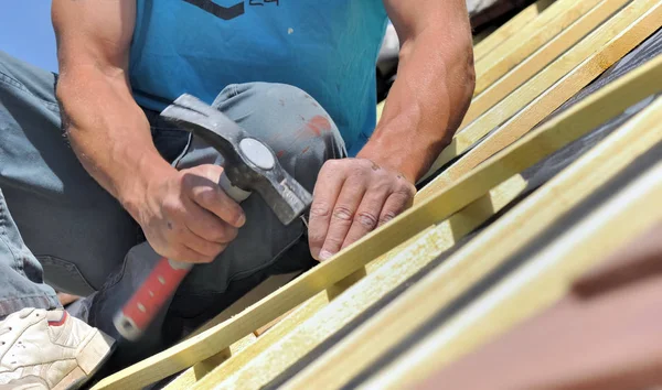 Vicino alle mani di un lavoratore inchiodare una lettiera per rinovare un tetto di una casa — Foto Stock