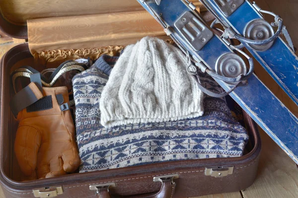 Esqui velho contra uma mala com roupa quente — Fotografia de Stock
