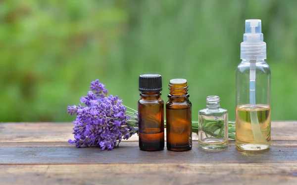 Verschiedene Flaschen Ätherisches Und Kleiner Strauß Lavendelblüten Auf Einem Holztisch — Stockfoto