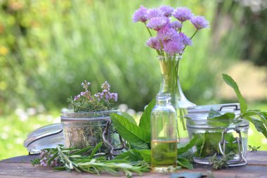 Cam kavanozlu aromatik bitki yaprağı ve bir bahçede masanın üzerinde duran yağ.