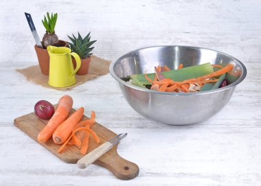 Mutfaktaki bir tabakta havuç soyuyorlar ve bir kase dolusu atık atıyorlar.  