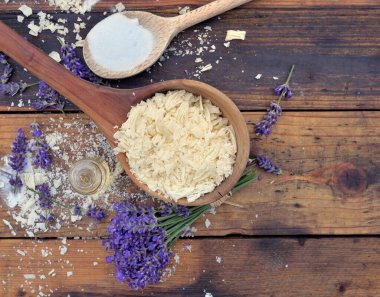 kaşık dolusu sabun ve ahşap zemin üzerinde lavanta çiçekleri.