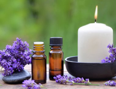 Ahşap bir masa üzerine dizilmiş, gerekli yağ şişeleri ve lavanta çiçekleri.