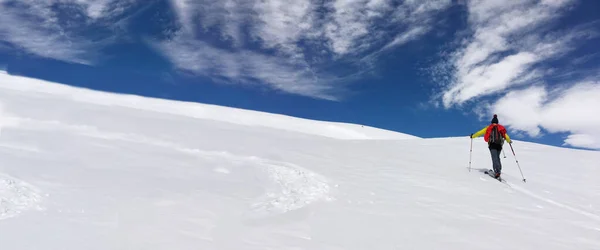 男子滑雪运动在蓝天和阴天下爬雪山 — 图库照片