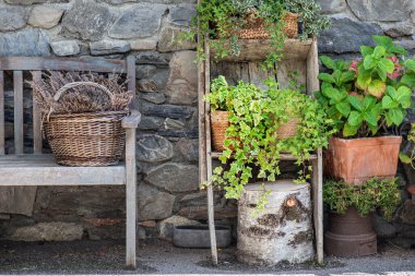 Bir evin dış dekorasyonu. Taş bir duvarın önüne bir bank yerleştirmiş. 