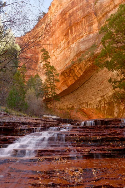 Beautiful waterfall streaming over red colored bedrock in the Left Fork North Creek, Zion National Park.