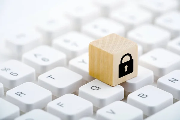 Wooden block with lock graphic on computer keyboard. Computer security concept.