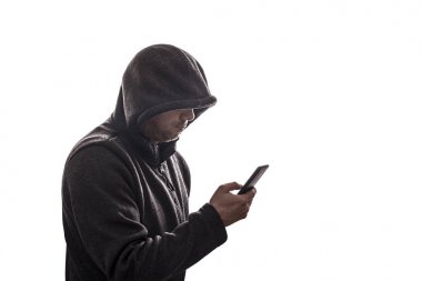 Kapüşonlu bilgisayar korsanı beyaz arka planda izole edilmiş akıllı telefonu tutuyor 