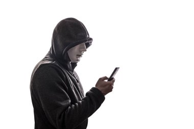 Maskeli bir bilgisayar korsanı beyaz arka planda izole edilmiş akıllı telefonu tutuyor. 