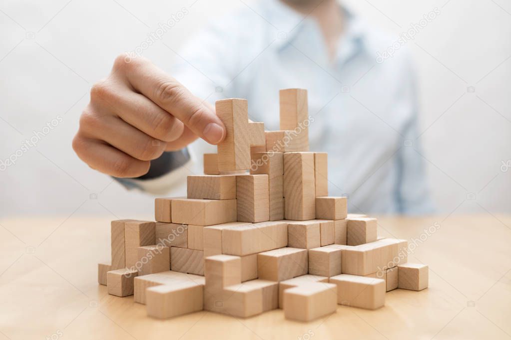 Man's hand stacking wooden blocks. Business development concept 