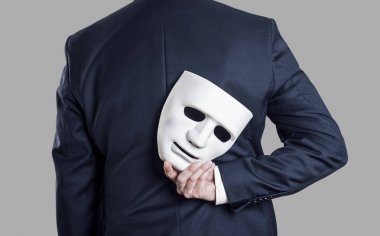 Business fraud concept. Businessman hide the mask in hand behind his back.  clipart